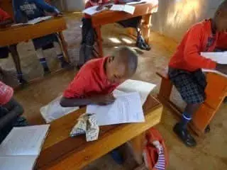 Dunclug PS - Kenya link up - pupils in Kenya in their classroom wearing read polo shirt uniform