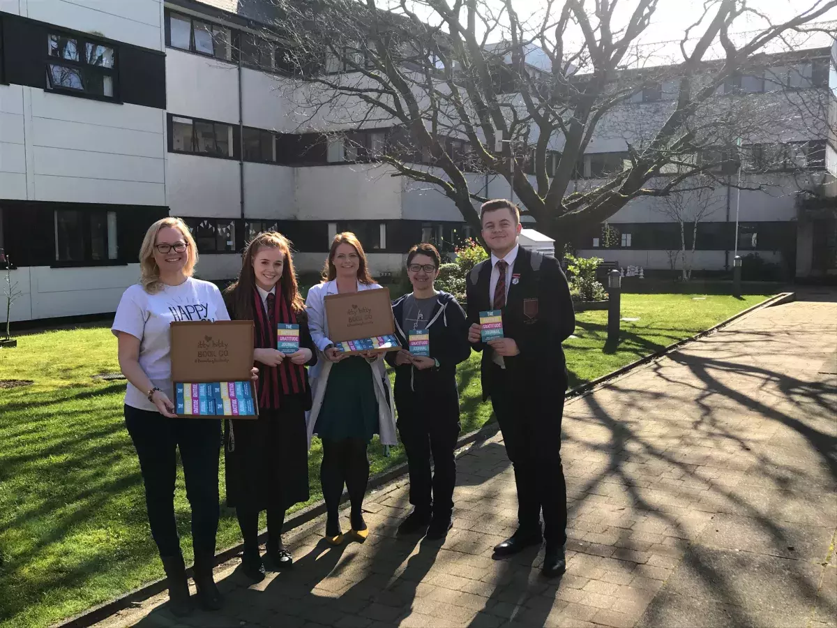 Staff and pupils of Ballyclare High School with gratitude journals from the Itty Bitty Book Co